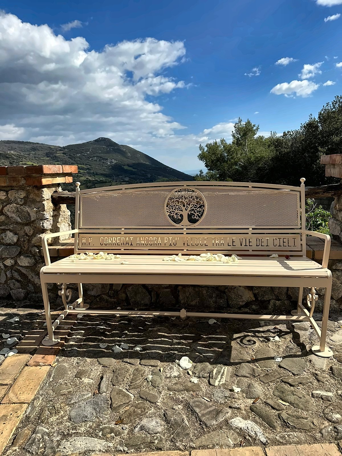 Panchina in ferro color crema con albero della vita e dedica incisa nello schienale, su un belvedere