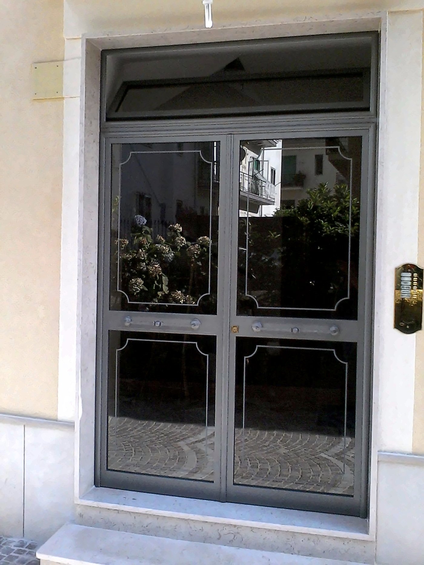 Portone d’ingresso in ferro e vetro con riquadri incisi per un condominio a Salerno